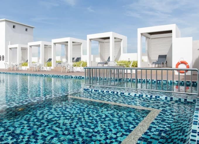 Rooftop pool area with cabanas and lounge chairs in a modern hotel, city not specified.